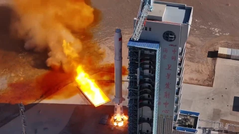 Motor reutilizable comercial de 240 toneladas de China durante una prueba de encendido en una plataforma de lanzamiento, con llamas y gases de combustión visibles.