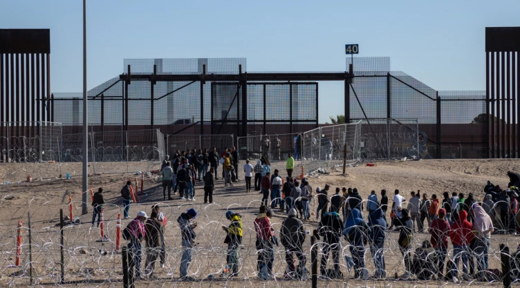 Personas hacen fila en la frontera entre México y Estados Unidos.
