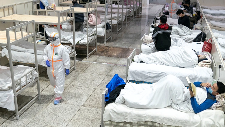 Medical workers in protective suits attend to patients at the Wuhan International Conference and Exhibition Center