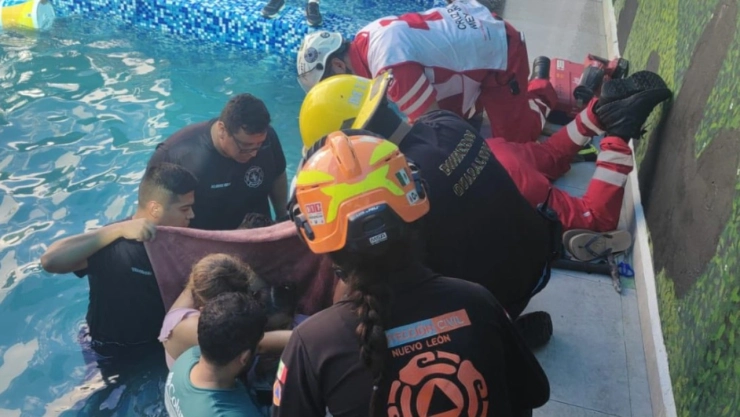Rescatan a niña atrapada en tubería dentro de alberca en Guadalupe, NL. En la imagen se observa cómo elemento de Protección Civil, Bomberos y familiares tratan de rescatar a la menor atrapada.