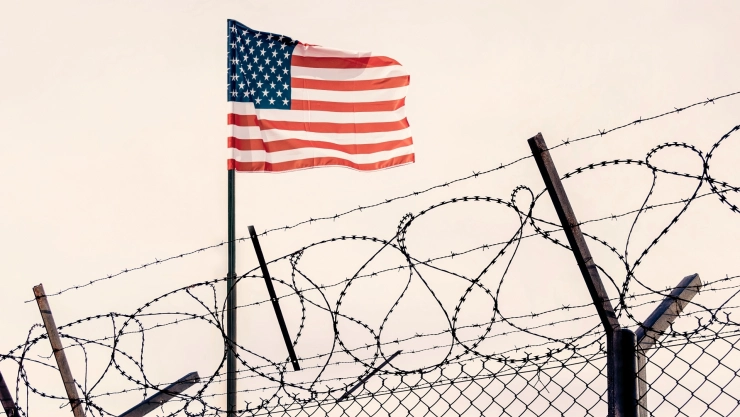 La frontera de Estados Unidos con una bandera y valla de alambre.