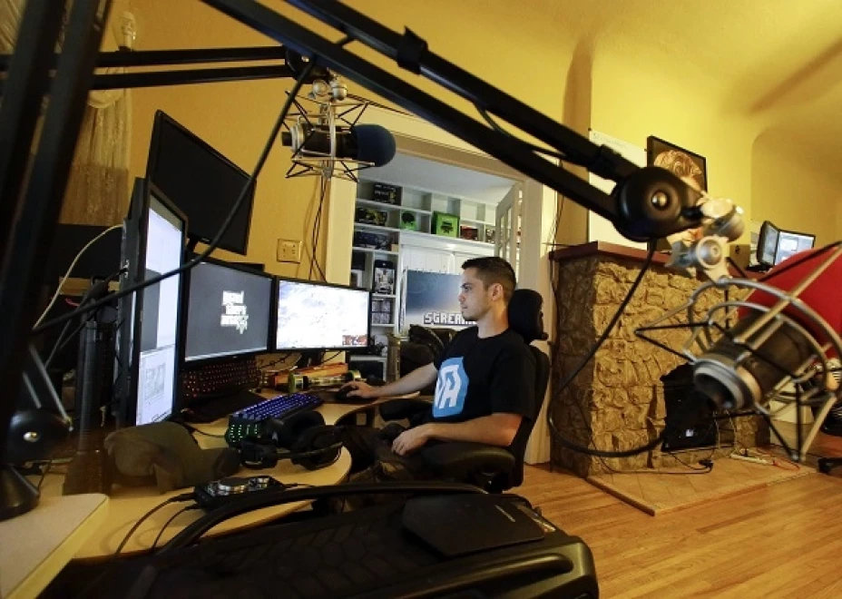 Adam Young observando varias pantallas de computadora mientras juega videojuegos para ganarse la vida