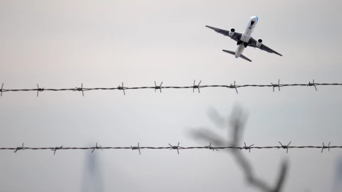 Un avión sobrevuela una valla de alambre.