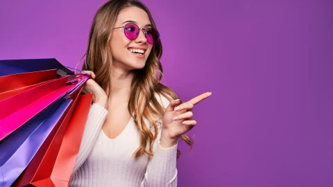 Beautiful smiling young blonde girl pointing in sunglasses holdi