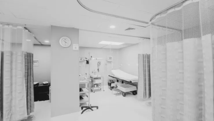 Cama de hospital con cortinas blancas.