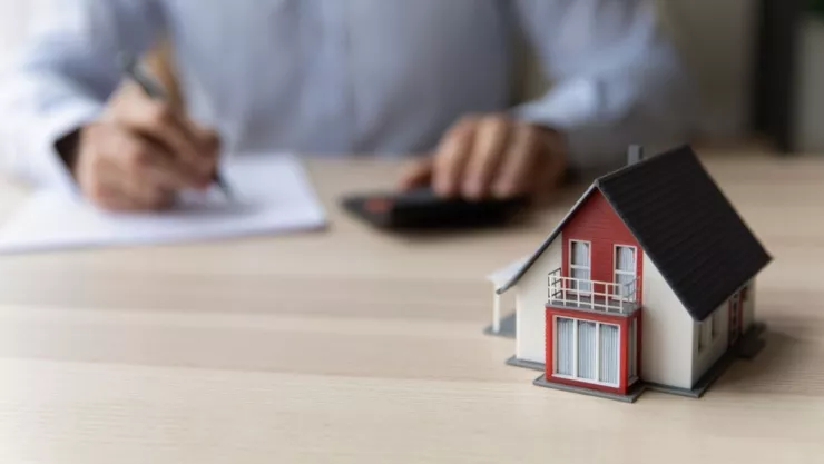 Una persona firma unos papeles y calcula gastos para la compra de una casa.