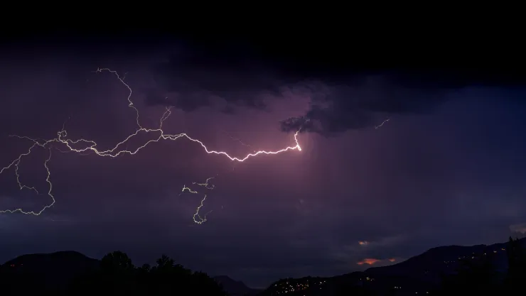 Imagen alusiva de una tormenta. Un cielo de noche iluminado por un rayo sobre un cerro