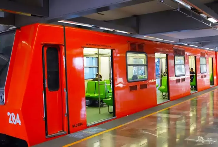 Un vagón naranja del Metro CDMX con los característicos asientos de color verde en su interior.