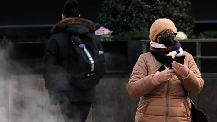 mujer abrigada con chamarra, bufanda y gorra