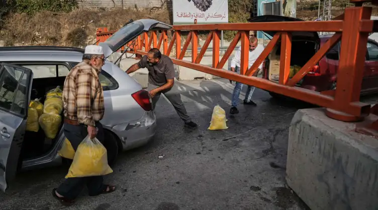 Palestinos frente a una barrera militar que cierra el paso en Hebrón, Cisjordania.