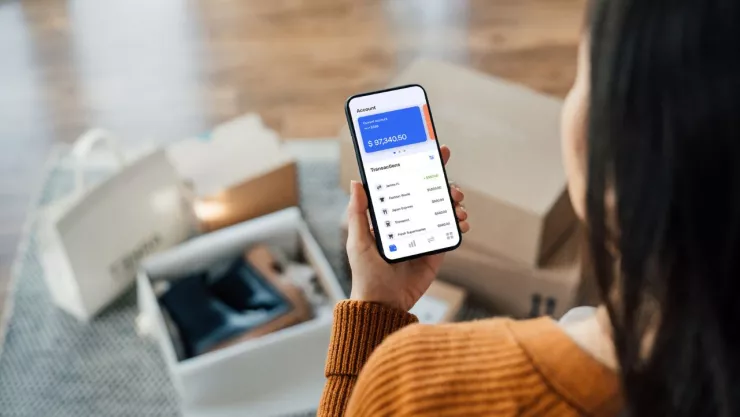Mujer sosteniendo un teléfono y rodeada de cajas con productos