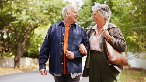 Pareja de adultos mayores caminan por la carretera.