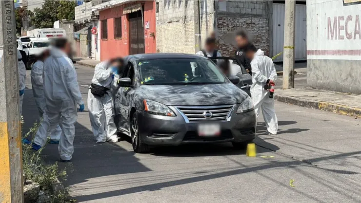 Peritos investigan auto en donde se encontraron los cuerpos de tres mujeres sin vida tras ataque armado.
