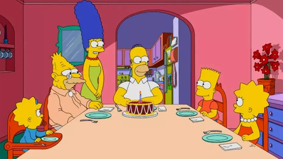 Una imagen de los Simpson reunidos en el comedor de su casa, en la mesa hay un pastel frente a Homero con una vela