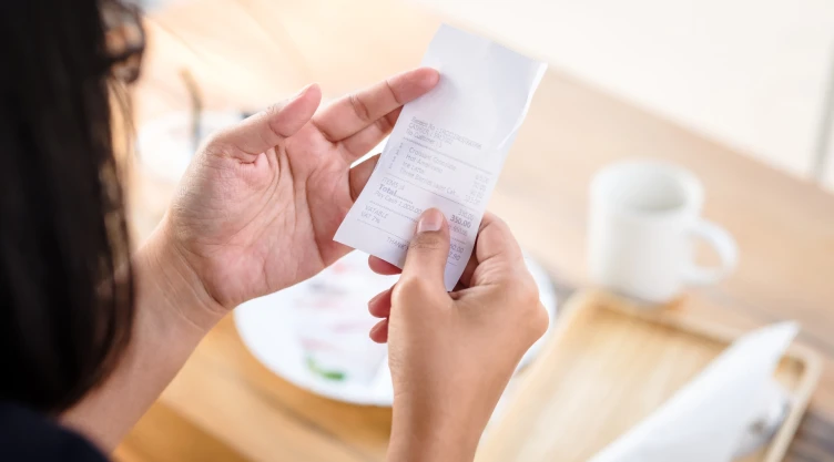 Una mujer revisa el ticket de su consumo