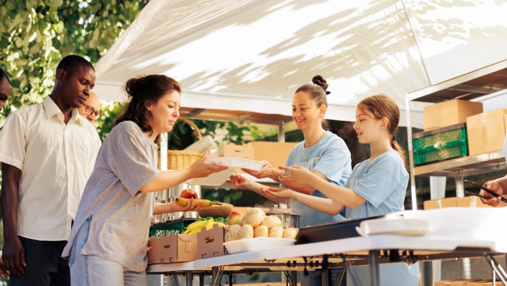 Dos mujeres le entregan alimentos a ciudadanos