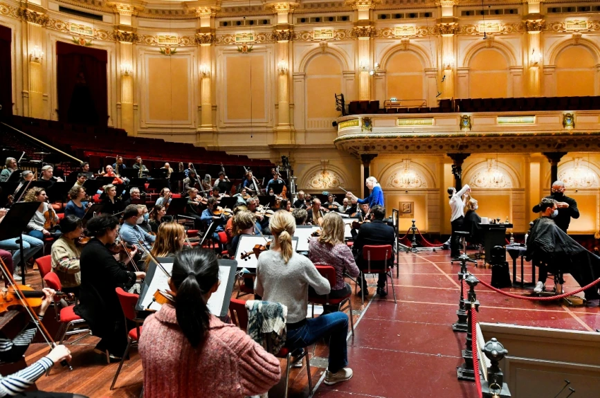 Las personas se cortan el cabello mientras toca una orquesta en vivo.