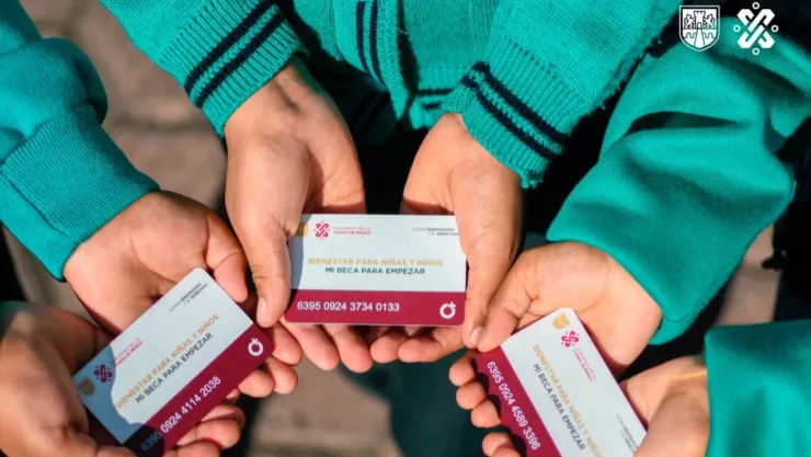 Manos de estudiantes de educación básica sosteniendo su tarjeta de Mi Beca para Empezar.