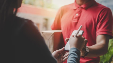 un repartidor entrega un paquete a una mujer.