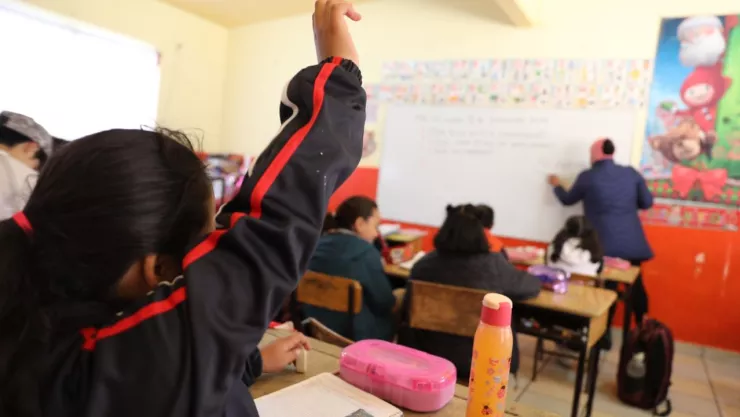Alumna de educación levanta la mano para participar en clase.