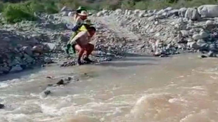 Maestro carga a alumnos para cruzar el río