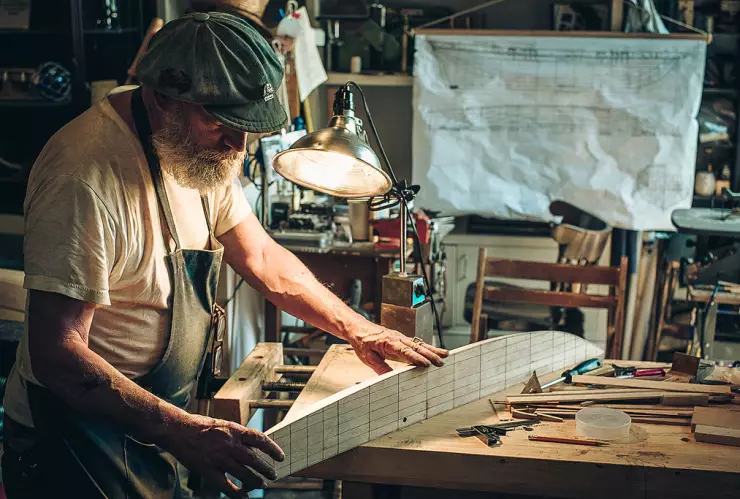 Old bearded man building wooden ship models