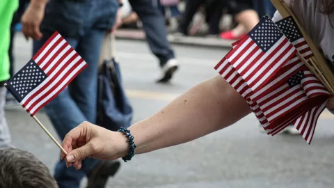 Una persona entrega banderas de Estados Unidos durante una celebración.