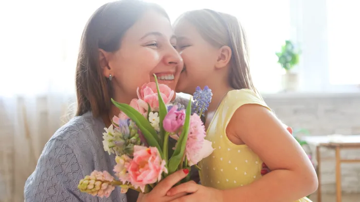 Una mamá con su hija y un ramo de flores.