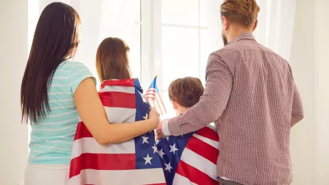 Una familia abraza unas banderas de Estados Unidos.