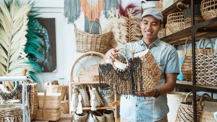 Un hombre mira uno de los bolsos artesanales que vende en su negocio, en Estados Unidos.