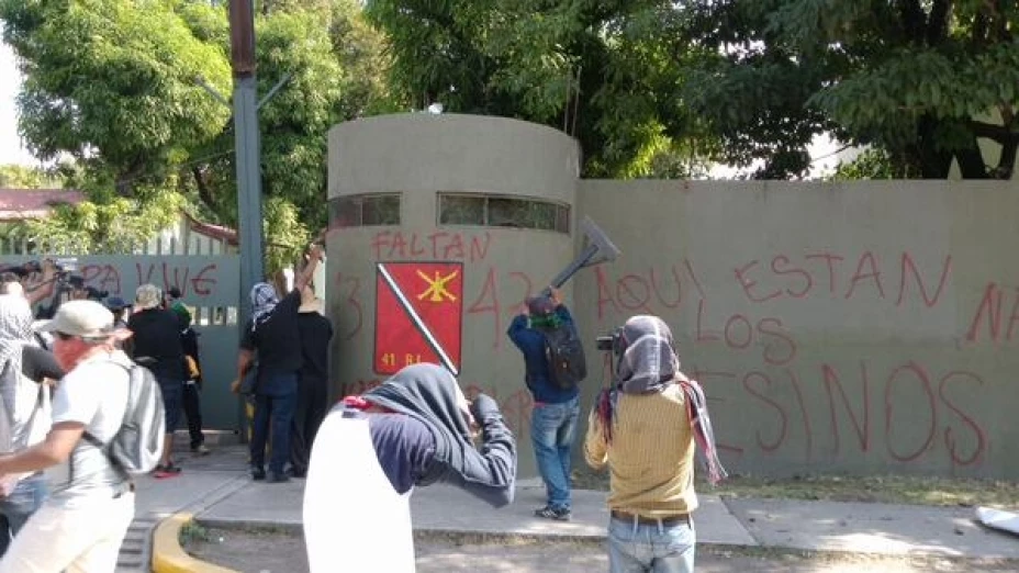 Durante la marcha por los 3 meses de la desaparición de los normalistas, familiares de los desaparecidos golpearon la puerta del edificio militar y lanzaron petardos.