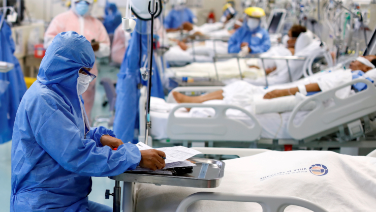 Un trabajador médico toma notas cerca de un paciente en la unidad de cuidados intensivos en Lima