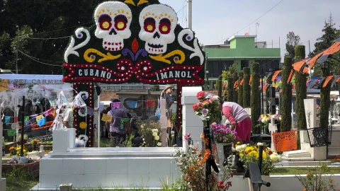 Mantienen tradiciones en panteones con flores, comida y música
