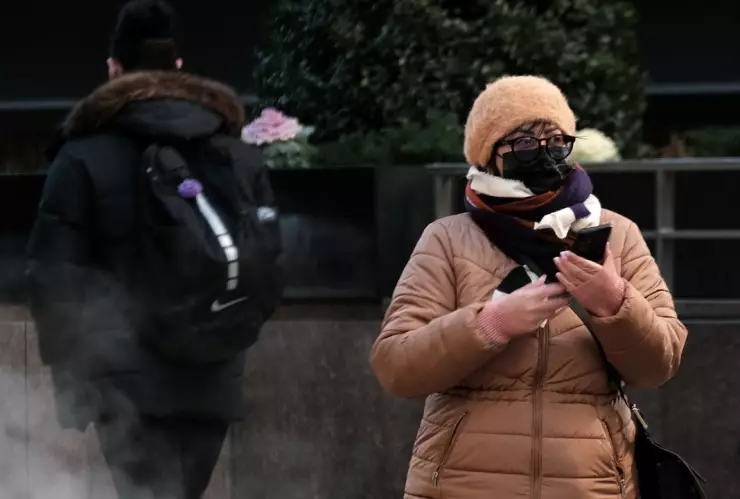mujer abrigada con chamarra, bufanda y gorra