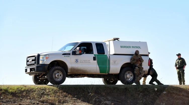 La patrulla fronteriza con tres agentes al rededor del vehículo