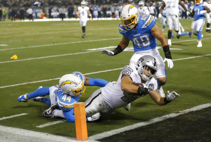 El running back de los Raiders de Oakland Alec Ingold consigue una anotación al superar a los linebackers de los Chargers de Los Ángeles Kyzir White y Drue Tranquill (49) en la primera mitad del juego del jueves 7 de noviembre de 2019, en Oakland,