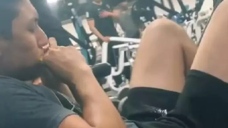 El joven que hace rutina de ejercicio en el gimnasio mientras come comida de PERRO