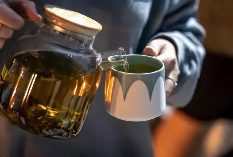 una mujer se sirve una taza de té