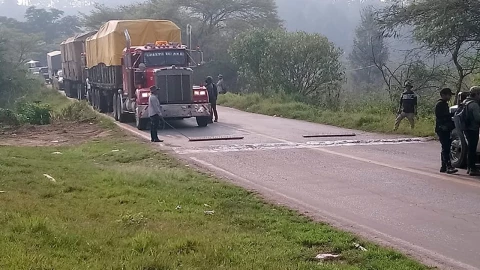 Camión en carretera sin avanzar por palos con clavos obstruyendo el paso.