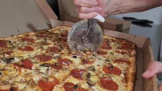 Una pizza recién hecha siendo cortada