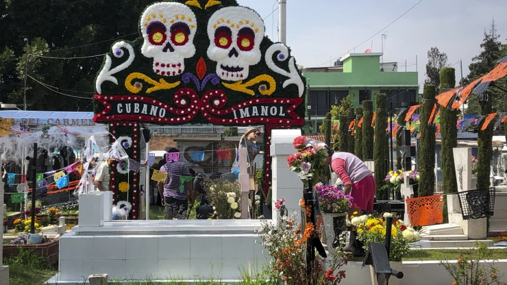 Mantienen tradiciones en panteones con flores, comida y música