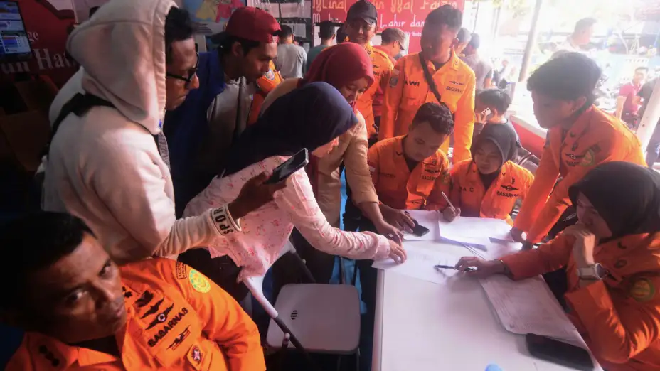 Personas buscan en lista de pasajeros a familiares tras el naufragio de un ferry en Indonesia.
