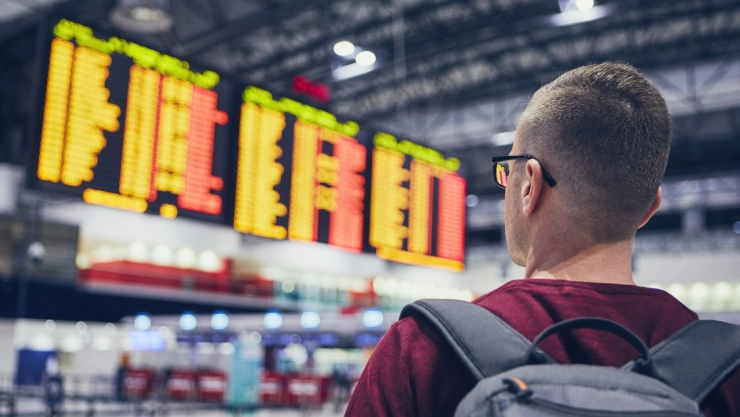 Un hombre ve la pantalla de horarios de vuelos en el aeropuerto