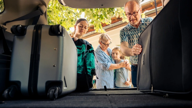 Una familia carga valijas en un auto