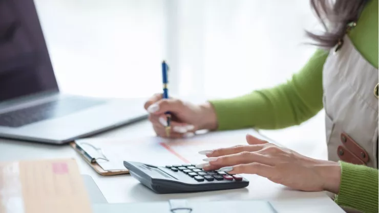 Una mujer hace cálculos financieros en su casa.