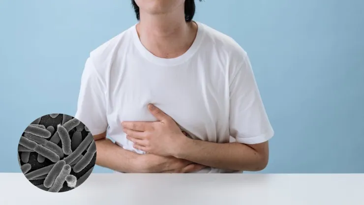 Joven sufriendo del estómago a lado de la toxina causante del cáncer de colón.