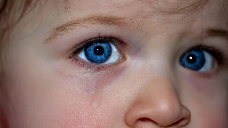 Niña de ojos azules con una lágrima en la cara.