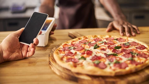 Un empleado presenta una pizza frente a un cliente.