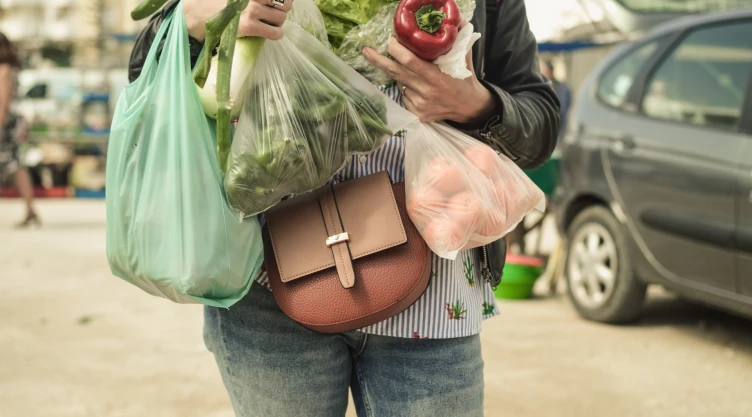 Una mujer con bolsas de plástico saliendo de un supermercado