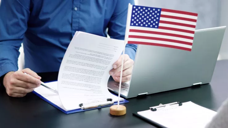 Una persona revisa una solicitud junto a una bandera de Estados Unidos.